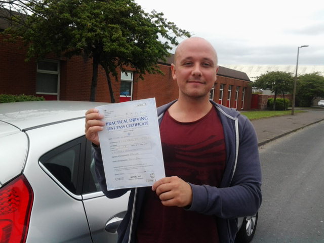 Student proudly displaying driving test pass certificate in Manchester